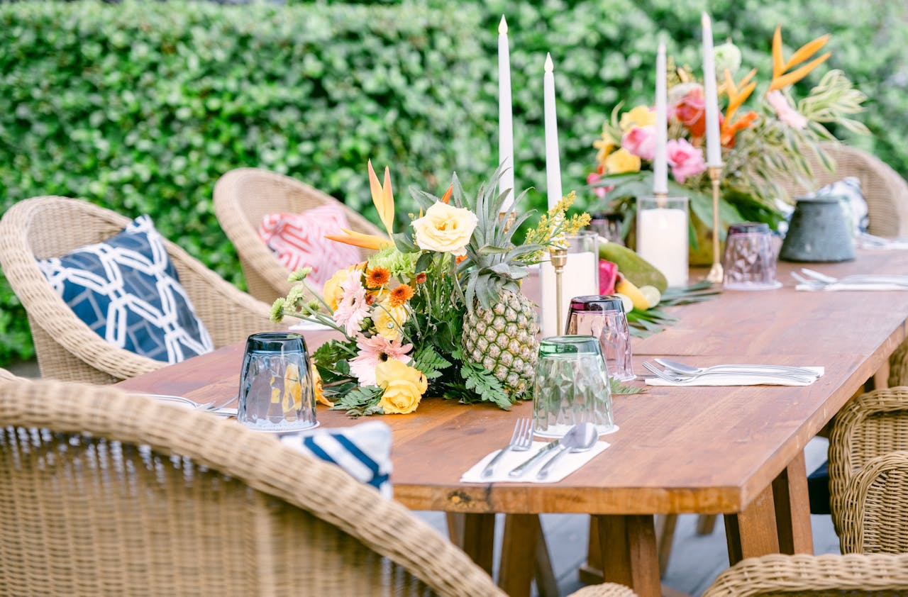 Elegant outdoor dining table with tropical floral arrangements and wicker chairs.